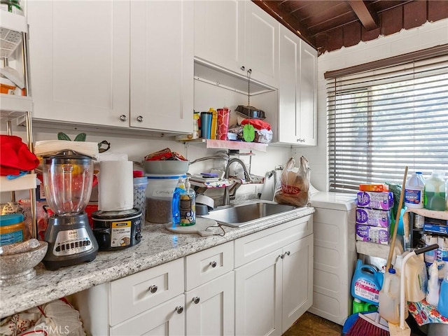 kitchen featuring white cabinetry, a sink, and light stone countertops