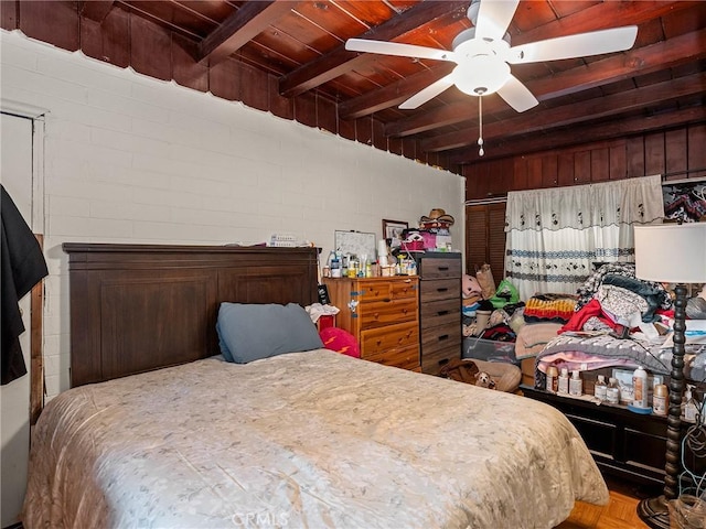 bedroom featuring beamed ceiling, wood ceiling, and a ceiling fan