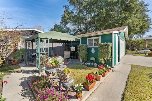 exterior space with an outbuilding, fence, a front lawn, and a patio