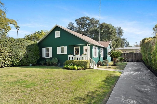 bungalow-style house with a front lawn, fence, and stucco siding