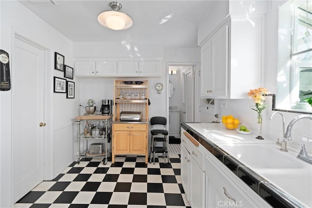 kitchen featuring dark floors, a sink, and white cabinetry