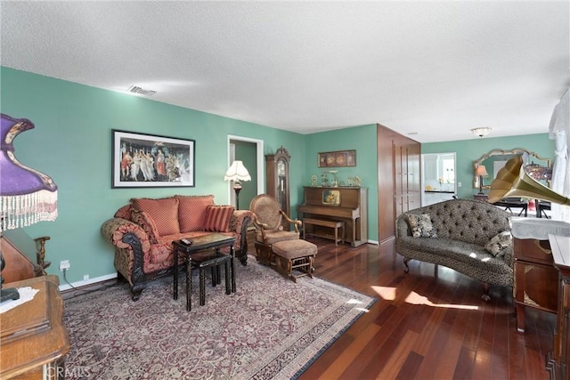 living room featuring dark wood-style floors, baseboards, visible vents, and a textured ceiling