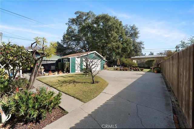 view of yard featuring a garage, fence, and an outbuilding