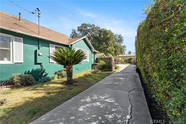 view of home's exterior with a yard, fence, and stucco siding