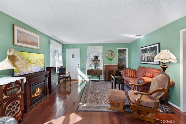 living room with a glass covered fireplace, dark wood finished floors, and a textured ceiling