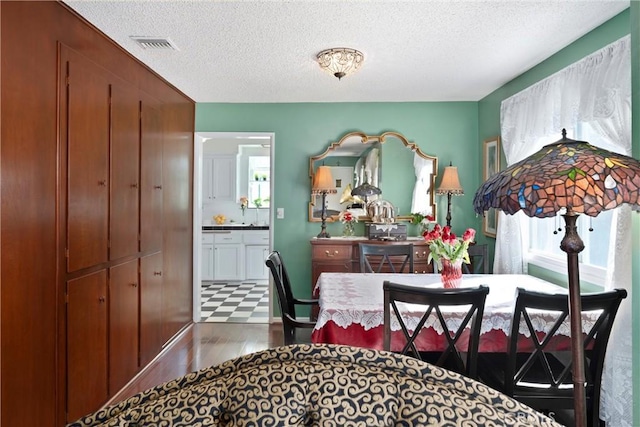 dining room with a textured ceiling, dark wood finished floors, and visible vents