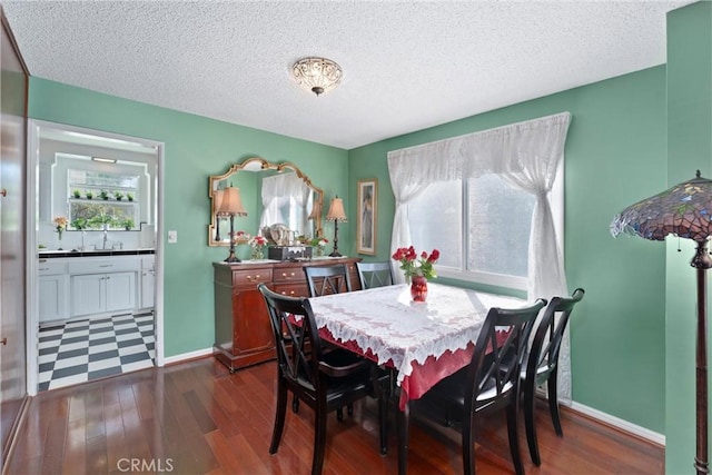 dining space featuring dark wood-style flooring, a textured ceiling, and baseboards