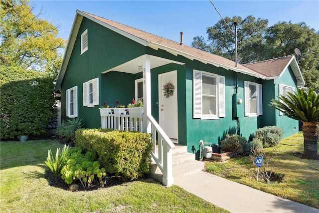 bungalow with a porch, a front lawn, and stucco siding