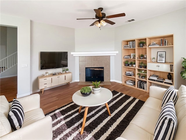 living room featuring a fireplace, wood finished floors, visible vents, and a ceiling fan