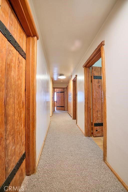 hallway featuring baseboards and light colored carpet