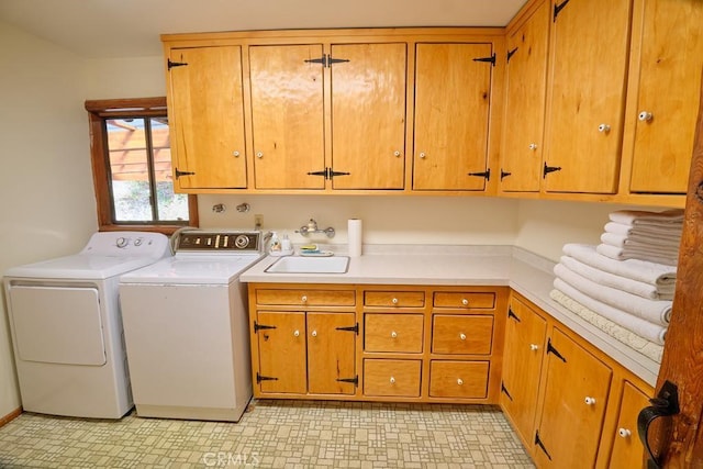 washroom with cabinet space, washer and dryer, light floors, and a sink