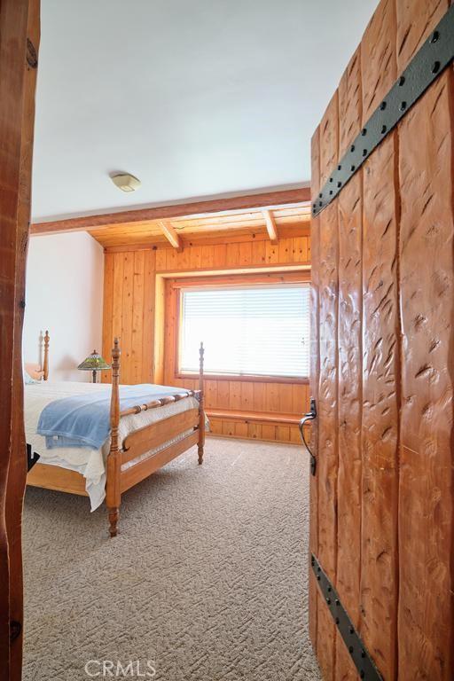 carpeted bedroom with wood walls