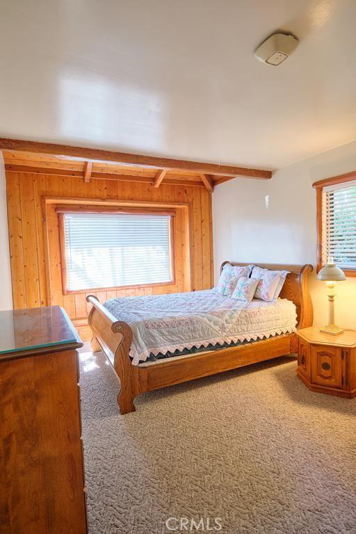 carpeted bedroom featuring wooden walls