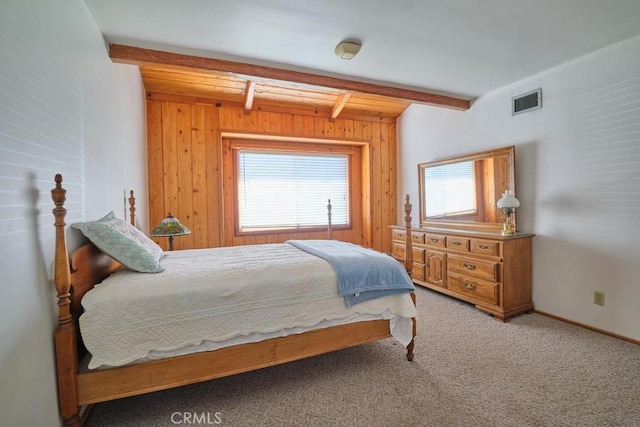 bedroom featuring carpet flooring, visible vents, wooden walls, and beam ceiling