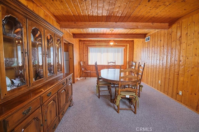 dining space with wood walls, wood ceiling, beamed ceiling, and carpet floors