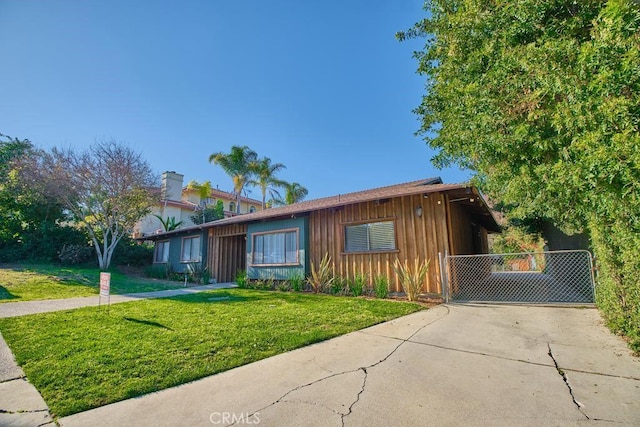 single story home featuring board and batten siding, driveway, a front yard, and a gate