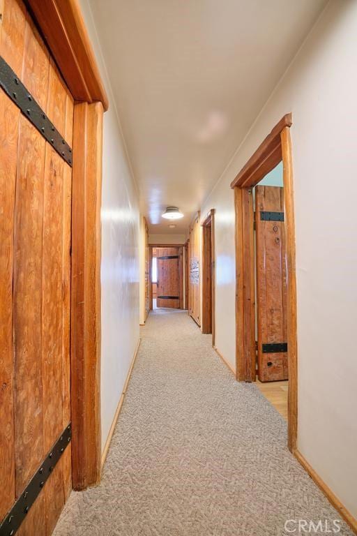 hallway with light colored carpet and baseboards