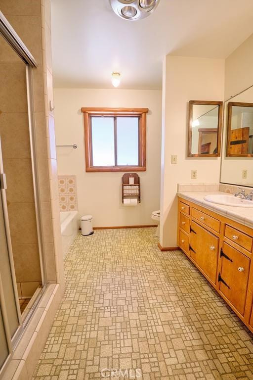 bathroom with baseboards, toilet, a shower stall, vanity, and a garden tub