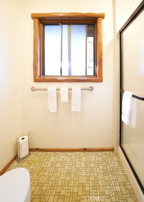 bathroom featuring toilet, baseboards, and a shower stall