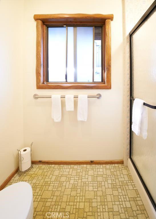 bathroom with toilet, baseboards, and a shower stall