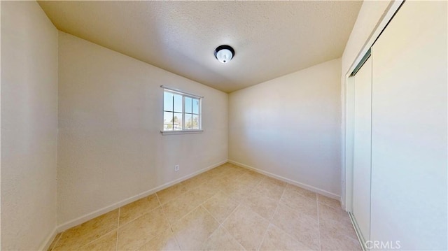 unfurnished room featuring a textured ceiling and baseboards