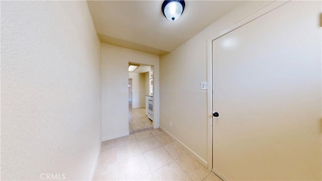 corridor with baseboards and light tile patterned floors