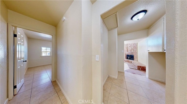 hall featuring light tile patterned flooring and baseboards