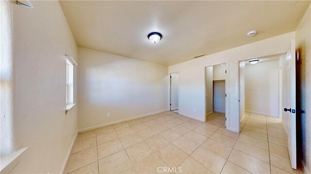 unfurnished bedroom with light tile patterned floors, baseboards, and visible vents