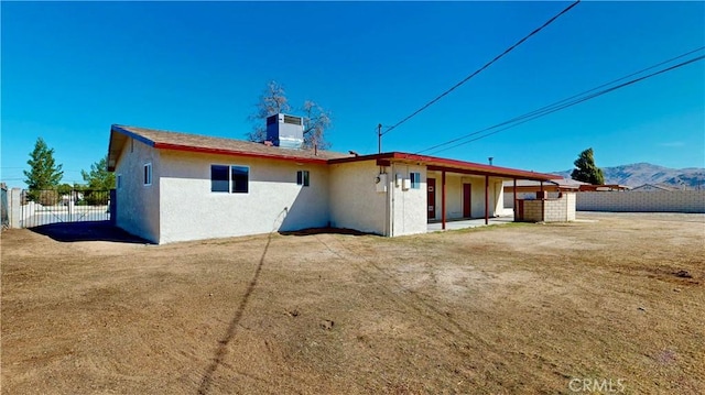 back of house featuring stucco siding, cooling unit, a mountain view, and fence