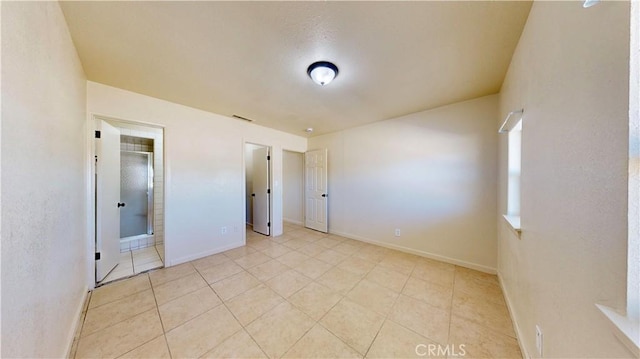 unfurnished bedroom featuring baseboards, visible vents, and light tile patterned flooring