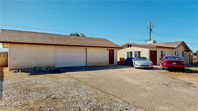 exterior space featuring a garage, roof with shingles, and stucco siding