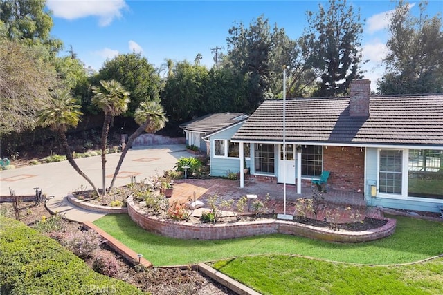 ranch-style home with a front yard, a tile roof, brick siding, and a chimney