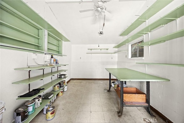 interior space featuring green cabinets, light floors, ceiling fan, and concrete block wall