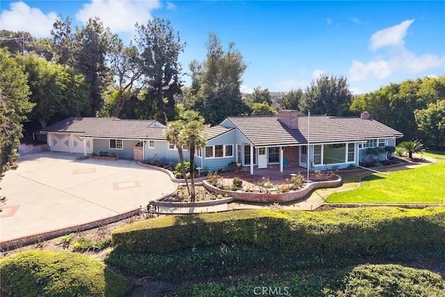 ranch-style home with driveway, a front lawn, a chimney, and a tiled roof