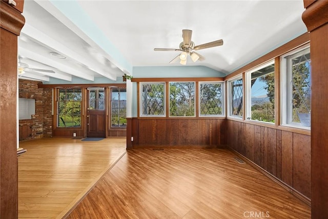 unfurnished sunroom featuring a healthy amount of sunlight, vaulted ceiling with beams, and a ceiling fan