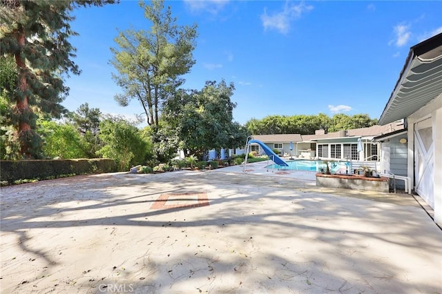 view of swimming pool featuring a fenced in pool, a water slide, and a patio