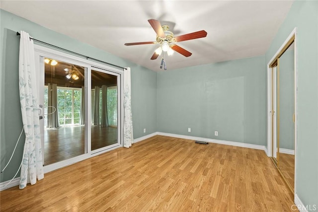 empty room featuring a ceiling fan, baseboards, visible vents, and light wood finished floors