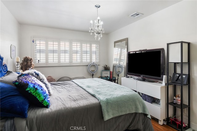 bedroom featuring a chandelier, wood finished floors, visible vents, and multiple windows