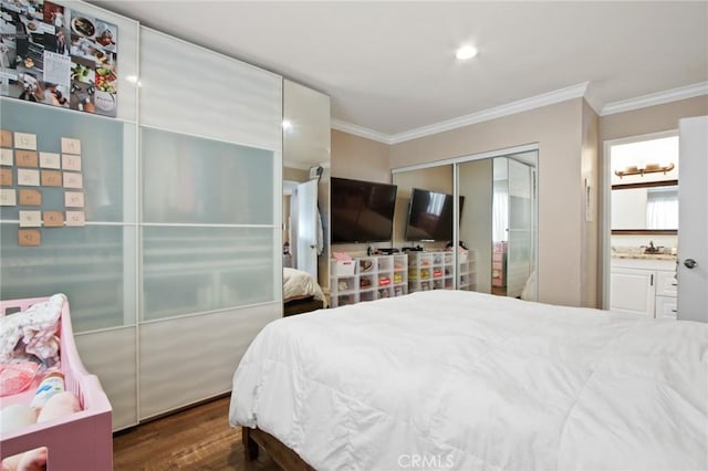 bedroom with ornamental molding, a closet, connected bathroom, and dark wood-style floors