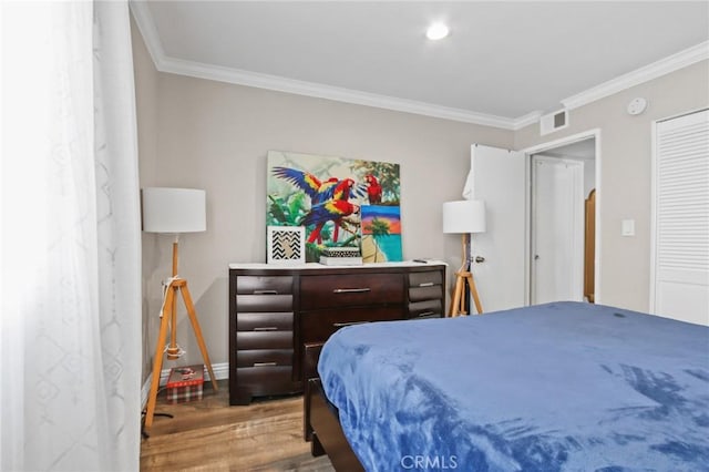 bedroom with visible vents, crown molding, baseboards, and wood finished floors