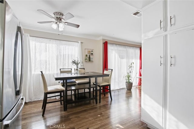 dining space with a ceiling fan, crown molding, visible vents, and dark wood-type flooring