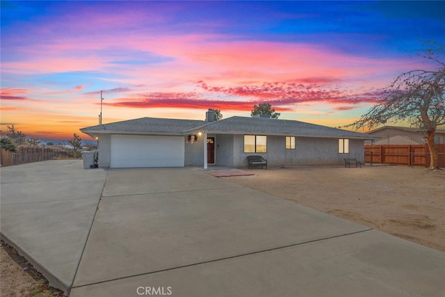 ranch-style house featuring an attached garage, driveway, and fence