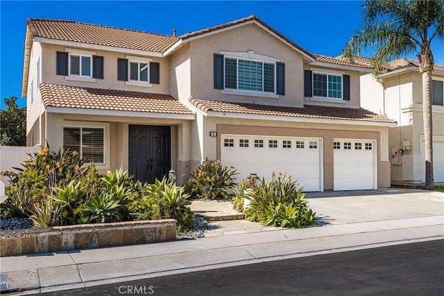 view of front of home with driveway, an attached garage, a tiled roof, and stucco siding