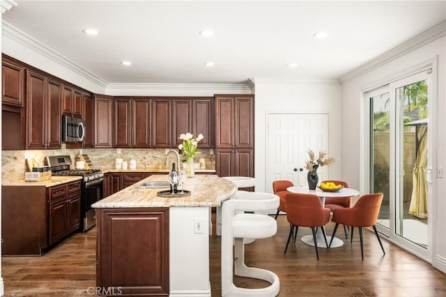 kitchen featuring tasteful backsplash, an island with sink, appliances with stainless steel finishes, wood finished floors, and a sink