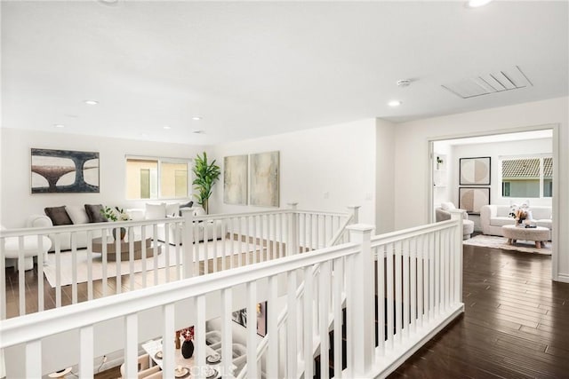 hallway featuring recessed lighting, wood-type flooring, and an upstairs landing