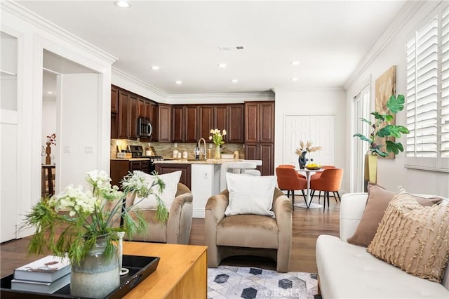 living area featuring recessed lighting, visible vents, crown molding, and light wood finished floors