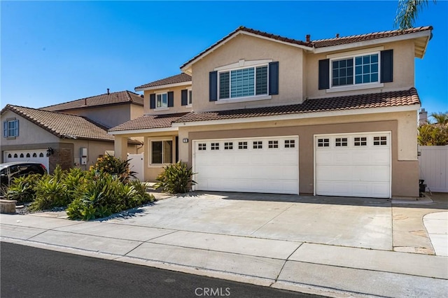 traditional home with an attached garage, a tiled roof, concrete driveway, and stucco siding