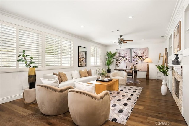 living room featuring a fireplace, visible vents, ornamental molding, wood finished floors, and baseboards