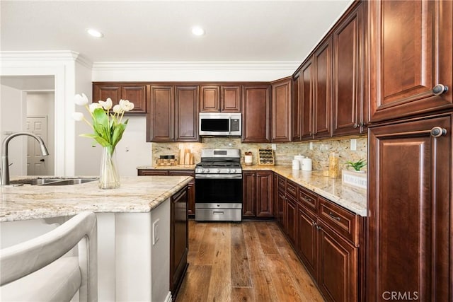 kitchen with tasteful backsplash, dark wood-style floors, light stone counters, stainless steel appliances, and a sink