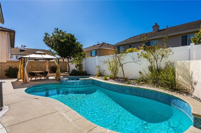 view of pool featuring a pool with connected hot tub, a fenced backyard, a patio, and a gazebo